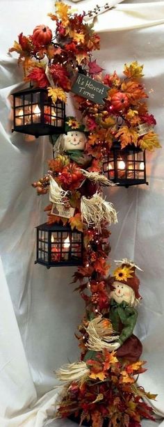 an arrangement of fall leaves and candles are arranged in the shape of a scarecrow