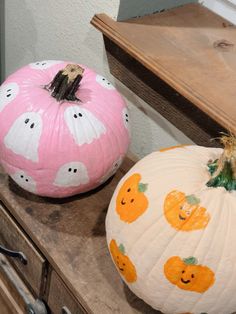 two painted pumpkins sitting on top of a wooden table