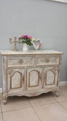 a white dresser with flowers on top and a heart shaped vase sitting on top of it