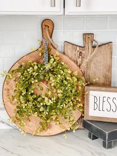 a cutting board with a wreath on it next to a sign that says blessing hanging from the wall