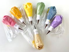 six different colored umbrellas in plastic bags on a white surface with one opened and the other closed