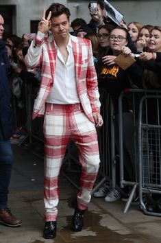 a man in a red and white checkered suit waves to the crowd as he walks