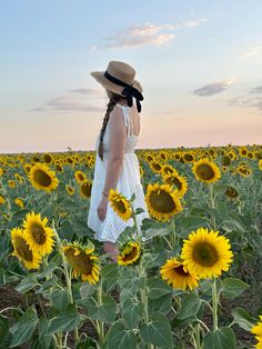 a woman standing in a field of sunflowers with her back to the camera