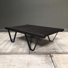 a wooden table sitting on top of a hard wood floor next to a gray wall