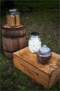 two jars sitting on top of a wooden crate next to a barrel filled with marsh