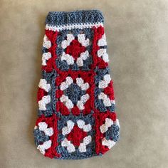 a red, white and blue crocheted blanket laying on the floor