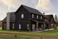 a large black house sitting on top of a lush green field next to a wooden fence