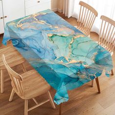 a dining room table covered in blue and gold marbled paper with chairs around it