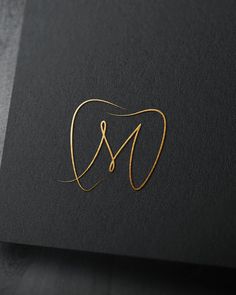 the letter m is made out of gold wire