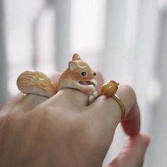 a person is holding a ring with a small animal on it's finger,