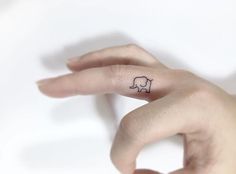 a woman's hand with a small elephant tattoo on her left thumb and finger