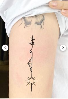 a woman's thigh with a tattoo on it that has a sun and tree