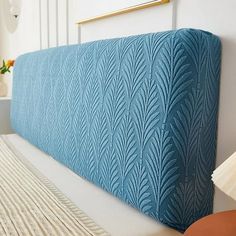 a close up of a bed with a blue headboard