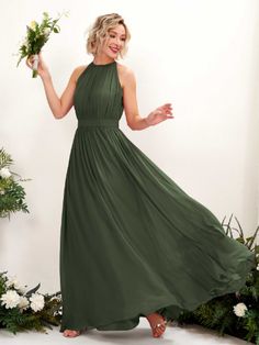 a woman in a long green dress holding flowers and smiling at the camera with her hand out