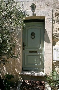 an olive tree in front of a green door