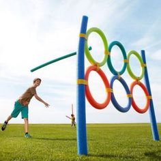 two children playing with an inflatable toy on the grass near a colorful sculpture