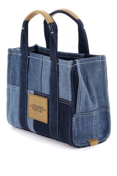 a denim bag with leather handles and two pockets on the front, one pocket is open