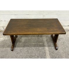 a wooden coffee table sitting on top of a carpeted floor next to a white wall