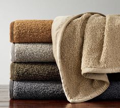 towels stacked on top of each other in various colors and sizes, with one folded over the edge