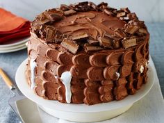 a chocolate cake sitting on top of a white plate next to a knife and fork