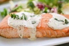 a piece of salmon covered in white sauce on a plate