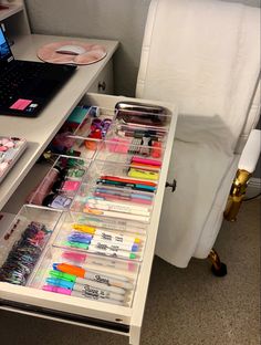 a desk with a laptop and many different items on it, including pens, markers, pencils and other office supplies