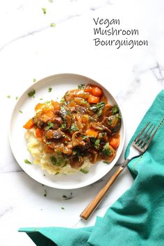 a white plate topped with mashed potatoes covered in mushrooms and vegtables