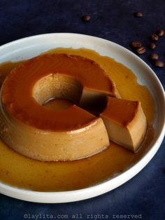 a bowl filled with caramel sauce on top of a blue table next to coffee beans