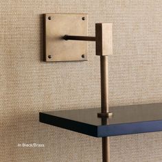 a wall mounted shelf with a metal hook on it's side next to a beige wall