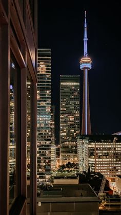 the city skyline is lit up at night, with skyscrapers in the foreground