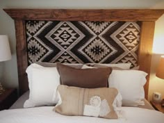 a bed with pillows and two lamps on either side of the headboard is made from wood