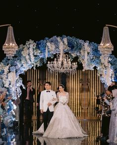 a bride and groom are walking down the aisle at their wedding in front of an elaborate chandelier