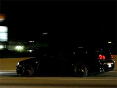 a black car driving down the road at night