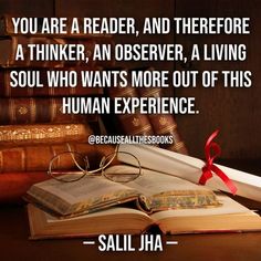 an open book sitting on top of a wooden table next to glasses and books with a red ribbon