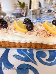 there are lemons and blackberries on top of this cake, which is topped with coconut