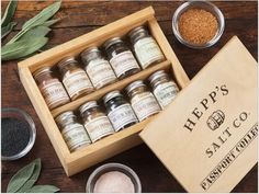 an assortment of spices and seasonings in a wooden box on top of a table