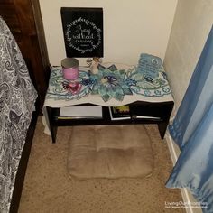 a small table with a blanket on it in a room next to a bed and curtains