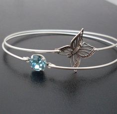 "Butterfly Jewelry by Frosted Willow. This listing is for the set of 2 dainty & delicate bangle bracelets. Choose silver tone butterfly filigree to be paired with an blue round rhinestone and bangle band choice of silver filled or sterling silver. Or choose a gold tone butterfly filigree paired with a blue round rhinestone and bangle band choice of brass or 14k gold filled. Personalize your butterfly bangle set with custom initial charms to create a customized butterfly charm bracelet. Perfe Handmade Delicate Blue Bracelets, Elegant Turquoise Adjustable Charm Bracelet, Light Blue Bangle Jewelry Gift, Light Blue Bangle Jewelry For Gift, Dainty Blue Bangle Jewelry, Dainty Blue Bangle, Light Blue Adjustable Dainty Jewelry, Dainty Blue Stackable Bracelets, Light Blue Bangle Bracelets As A Gift