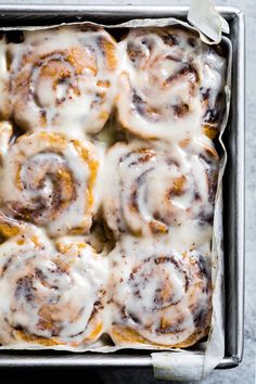 a pan filled with cinnamon rolls covered in icing