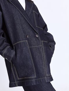 The Raha Denim Jacket brings a laid-back yet sophisticated touch to your workwear collection, featuring real horn buttons and an oversized fit for a modern edge. With practical front patch pockets and a fully functional closure, this unlined jacket effortlessly blends style and functionality. Layer it over a tailored shirt and wide-leg trousers for a polished look that balances comfort with contemporary flair. - Double-breasted, chest and front patch pockets, unlines, horn buttons- CmiA cotton- African Luxury, Contrast Topstitching, Indigo Colour, Workwear Jacket, Dresses Pants, Mini Shirt Dress, Slim Pants, Wide Sleeves, Skirted Swimwear