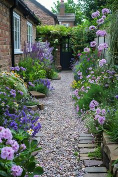 a garden with flowers and gravel path leading to a house