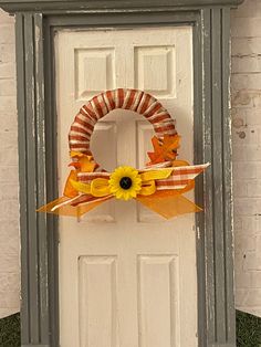 a white door with a wreath on it and an orange bow hanging from the front