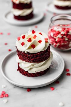 two red velvet cakes with white frosting and sprinkles on a plate