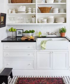 a kitchen with white cabinets and black counter tops is pictured in this image, there are dishes on the shelves