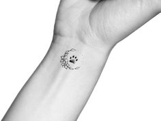 a black and white photo of a person's wrist with a dog paw tattoo on it