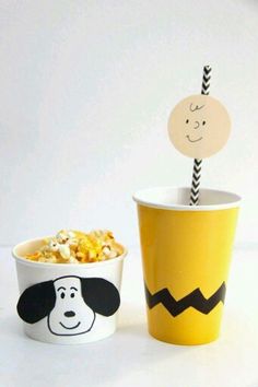 a bowl of popcorn and a cup with a face drawn on the side are sitting next to each other