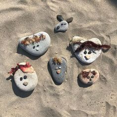 four rocks with faces are in the sand