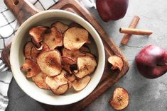 apple slices in a bowl next to an apple and cinnamon sticks