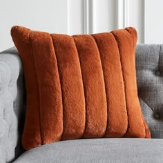 an orange pillow sitting on top of a gray couch