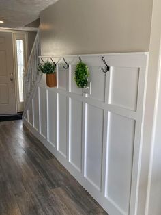 three potted plants are hanging on the wall next to a stair case with hooks